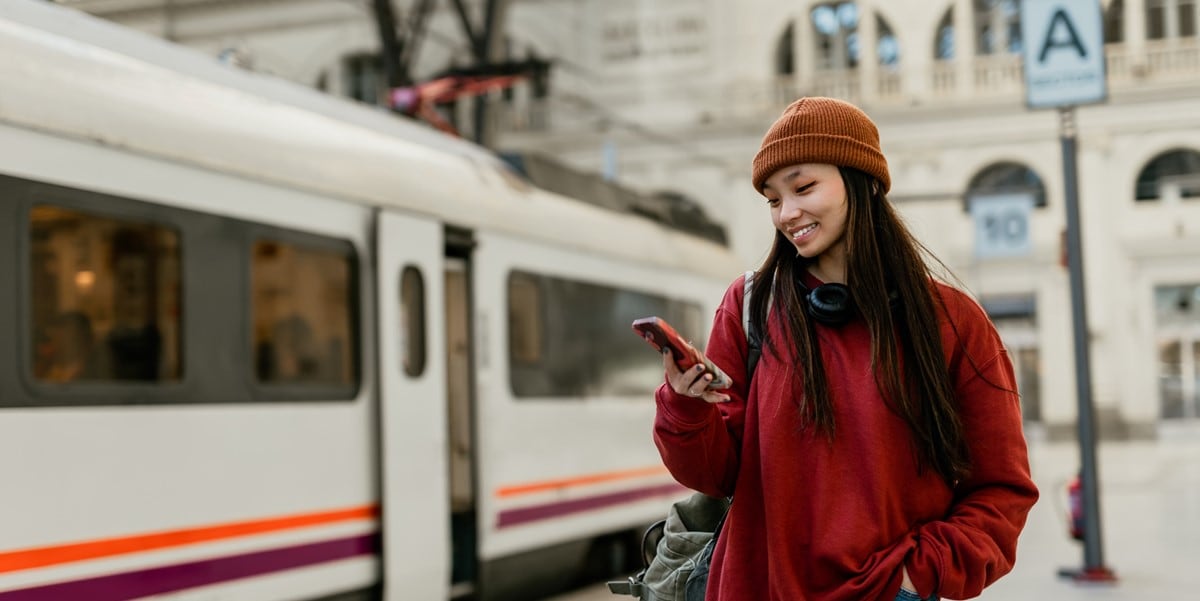 woman standing by bus, using cell phone
