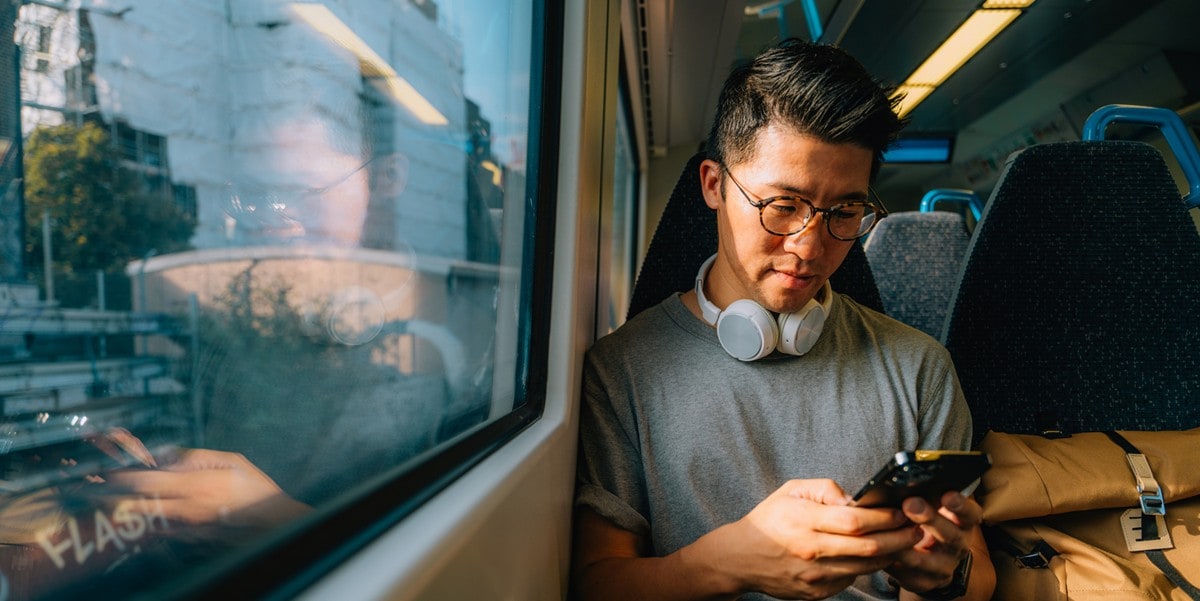 man sitting on train, using cell phone