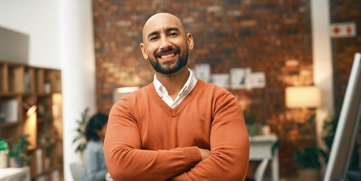 smiling man with arms crossed standing in an office