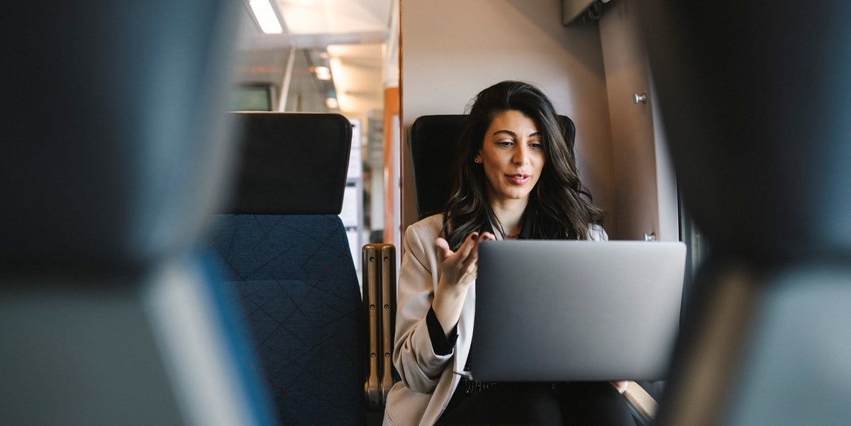 traveler on a train, seated, working on laptop