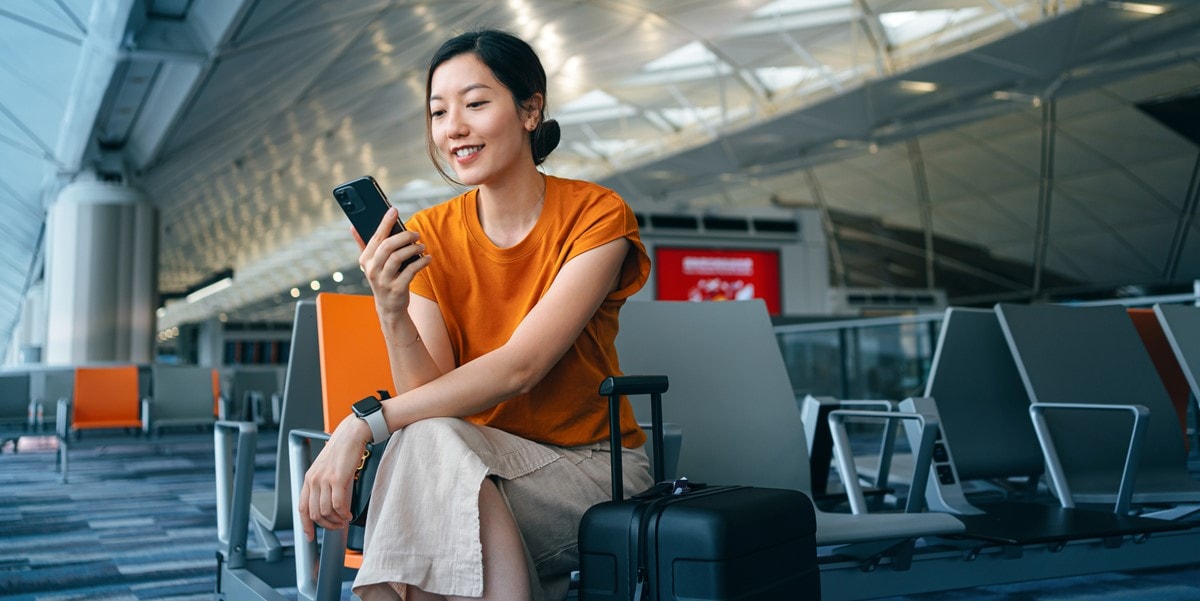 woman traveler sitting in airport lounge, using cell phone
