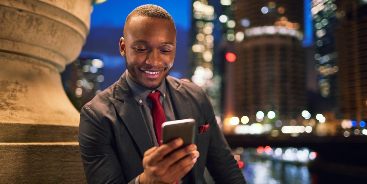 professional man sitting outside looking down at cell phone