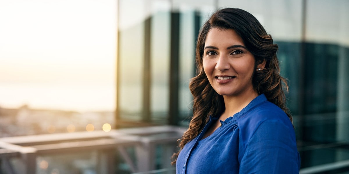professional woman smiling, standing in front of office building