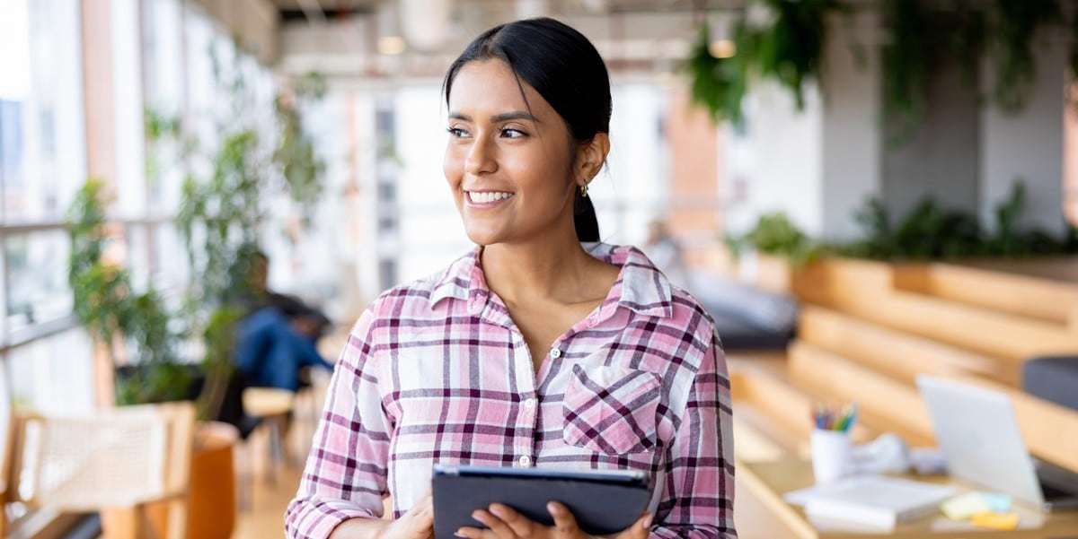 woman in the office smiling, holding a tablet