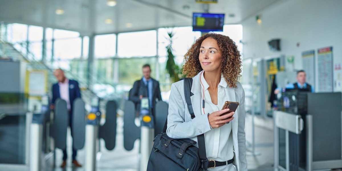 businesswoman walking through building lobby, holding cellphone