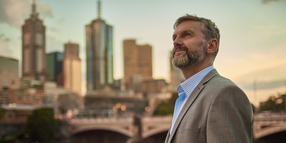 businessman standing outside, cityscape in the background