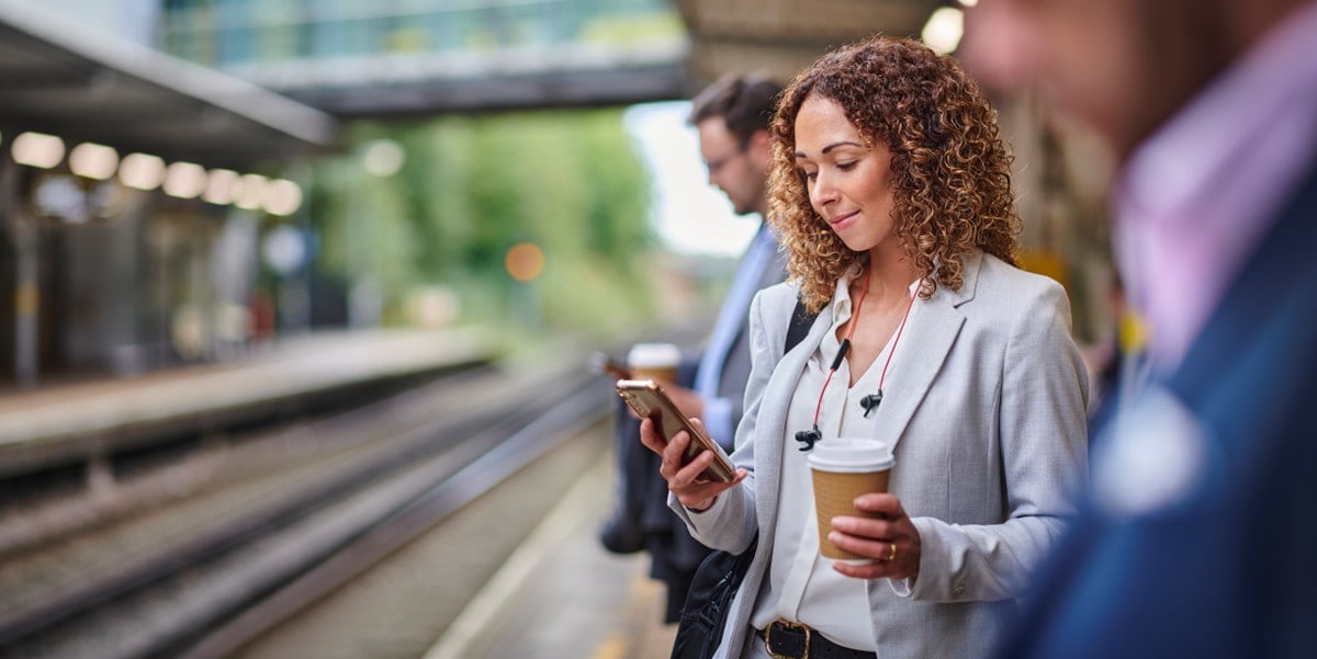 traveler waiting at train platform looking at phone