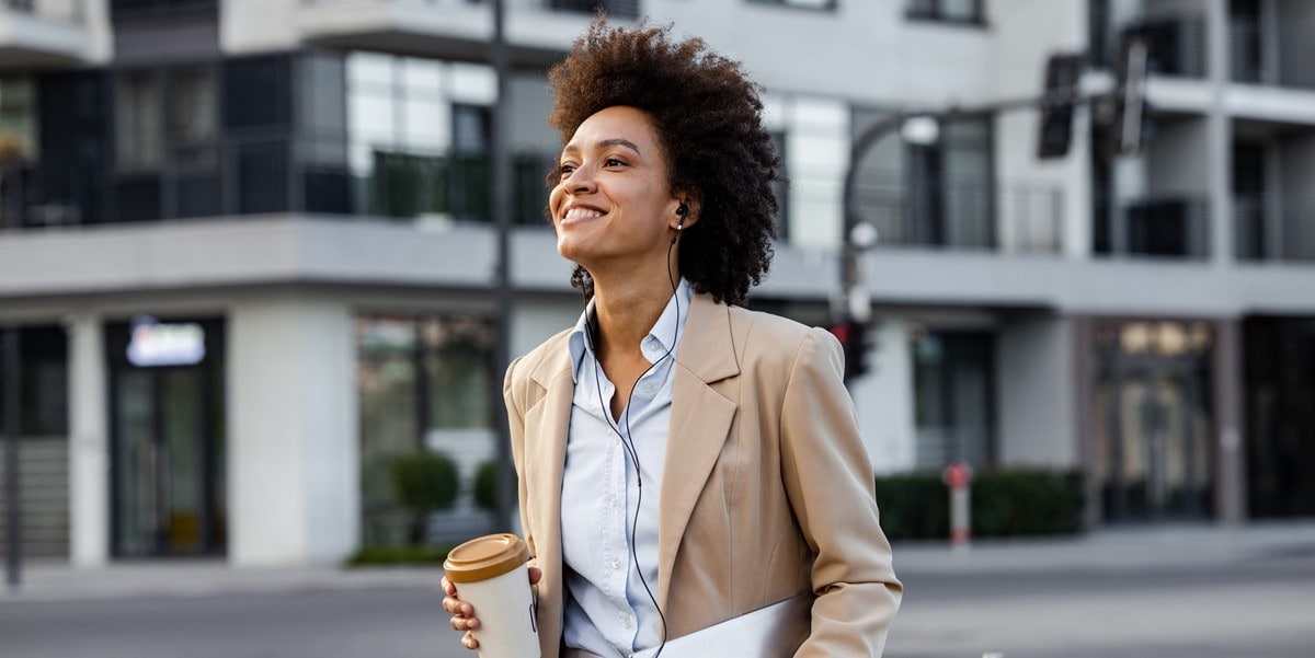 traveler in city, smiling, coffee cup and laptop in hands