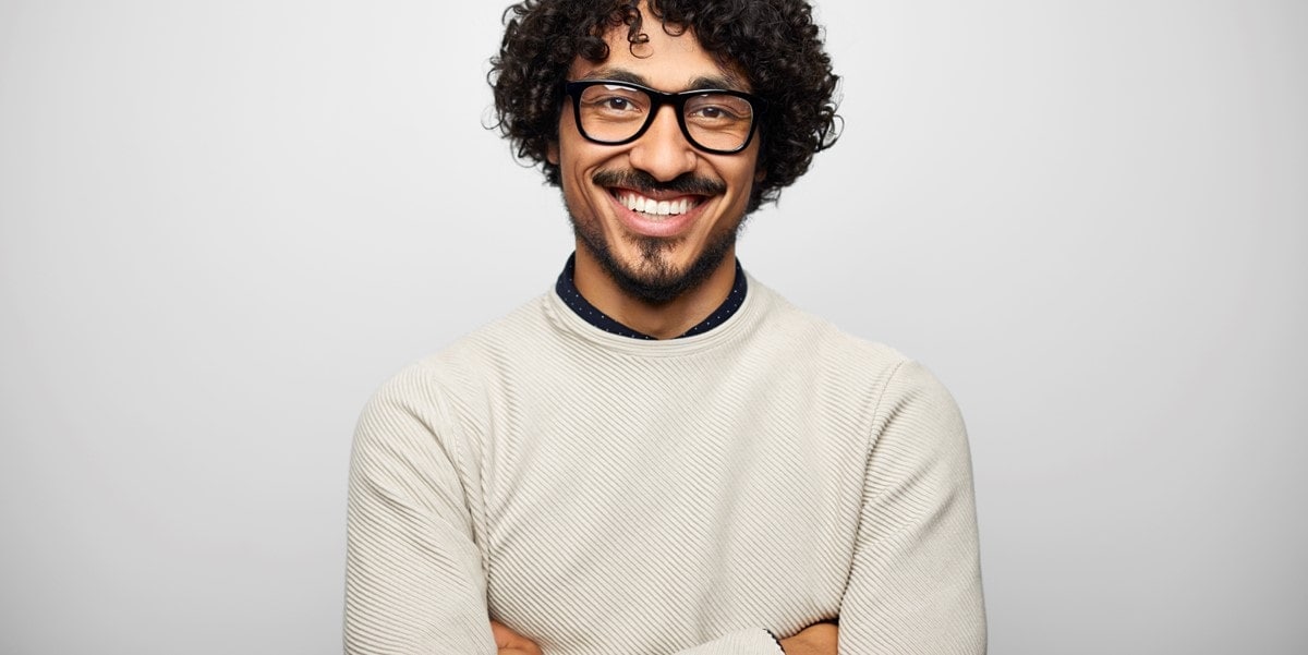man smiling with arms crossed in office setting