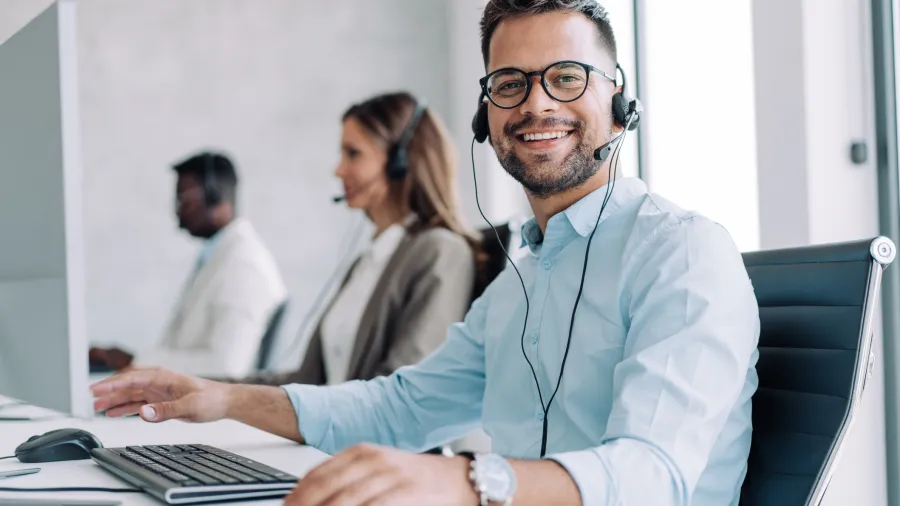 Man at computer with headset looking at camera