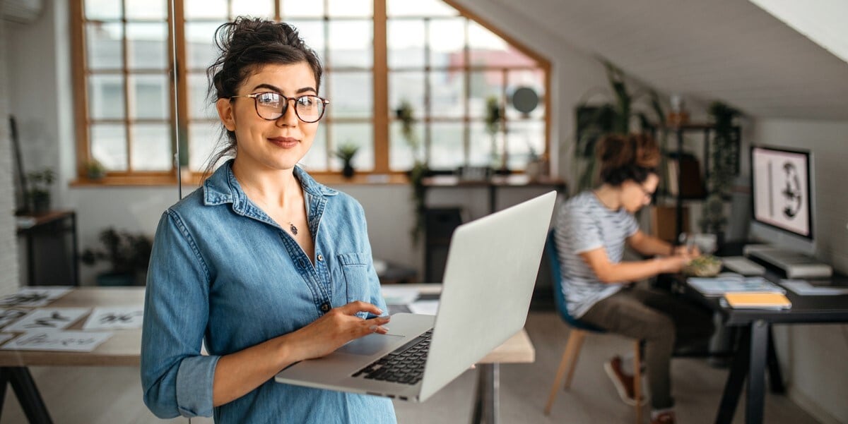 woman in office holding laptop