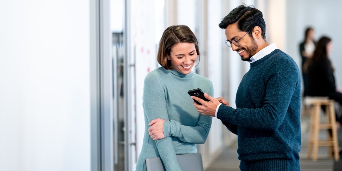 two people in office looking at cell phone 