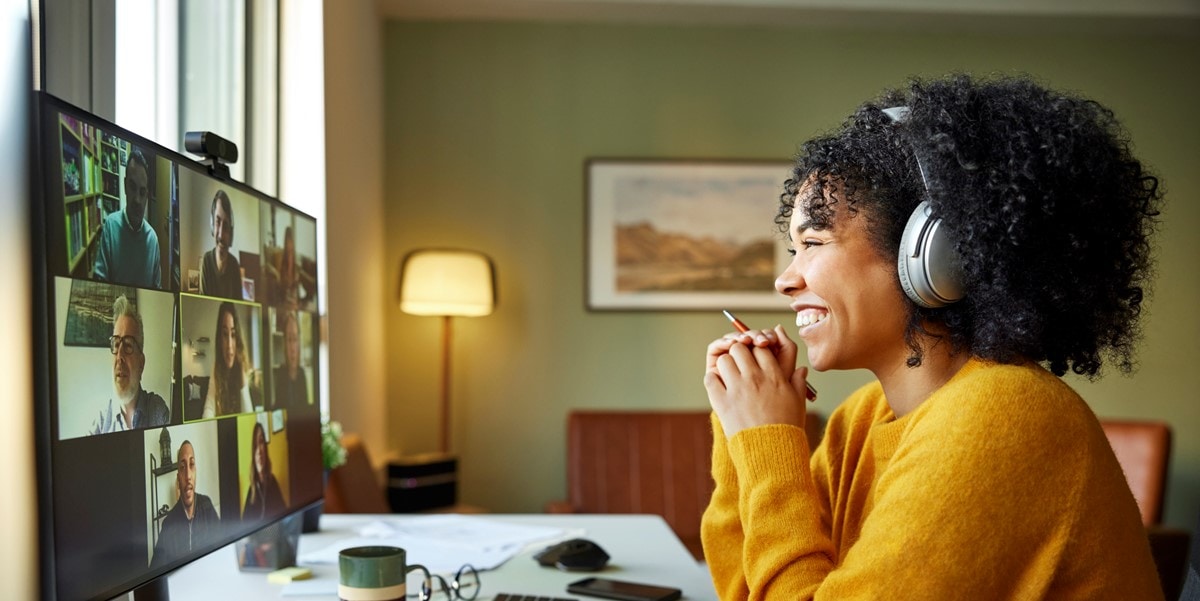 smiling woman in virtual meeting with headphones on