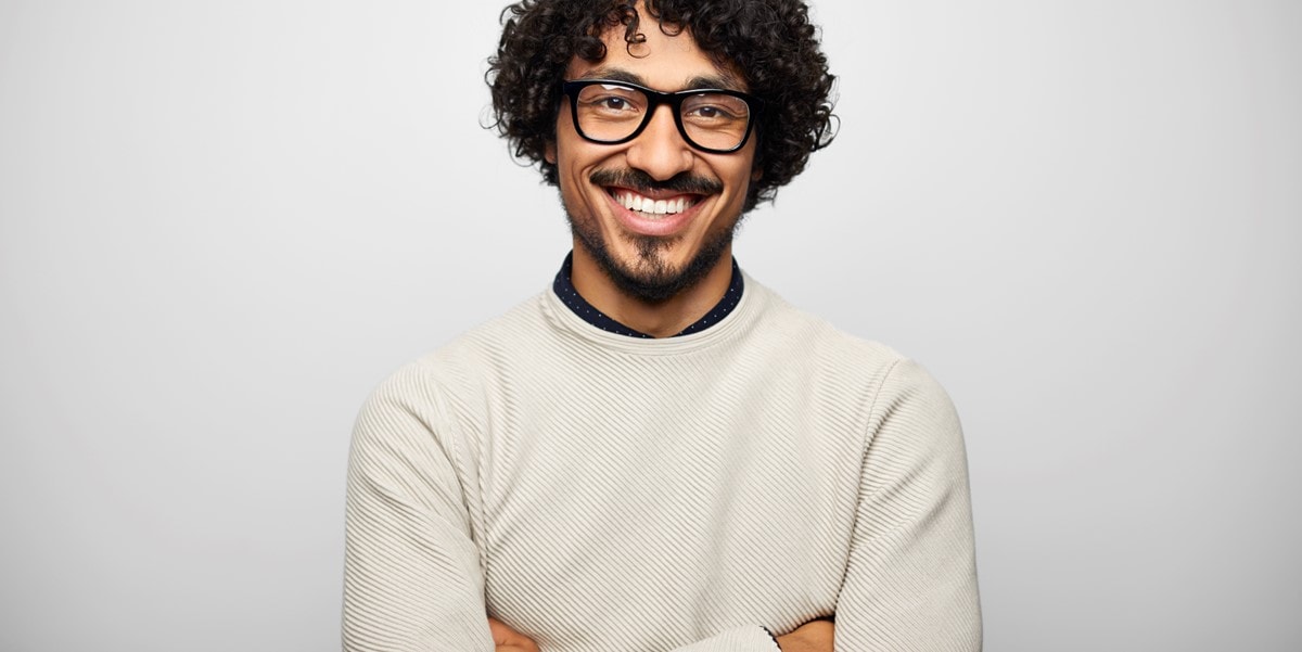 man smiling with arms crossed in office setting