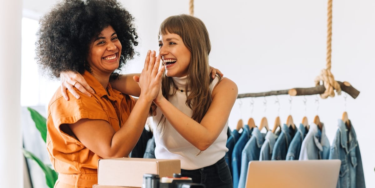 two women smiling and high fiving