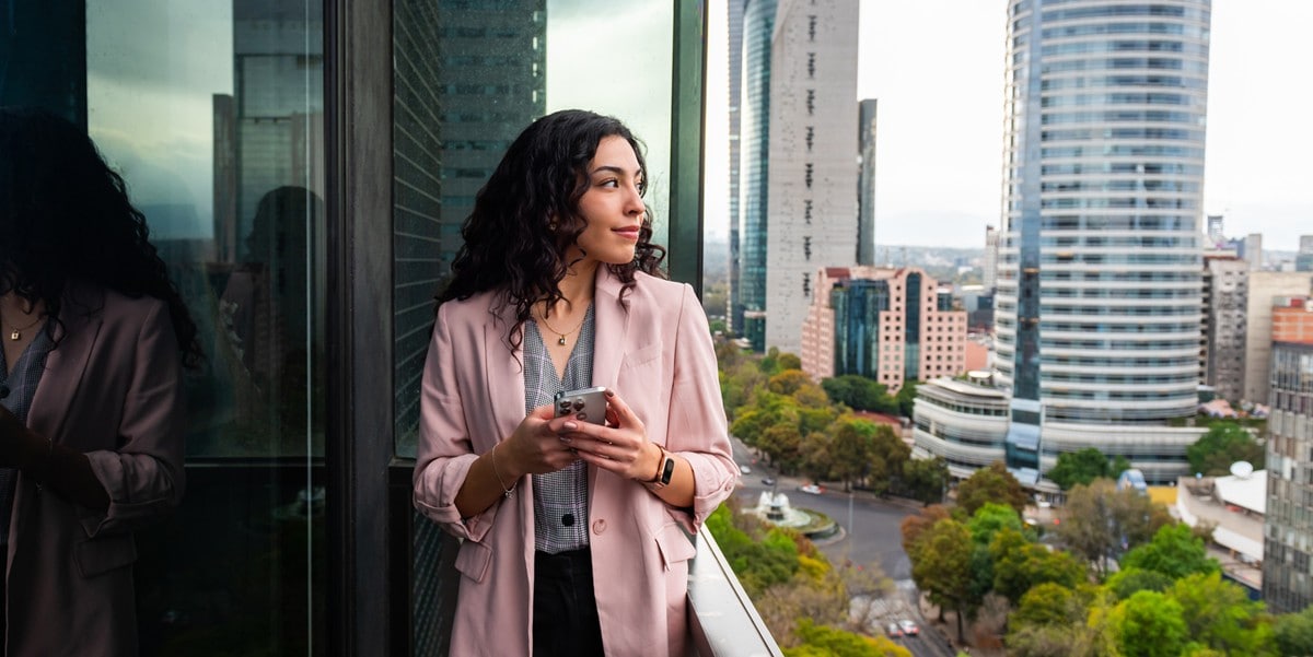 professional woman standing on balcony, phone in hand