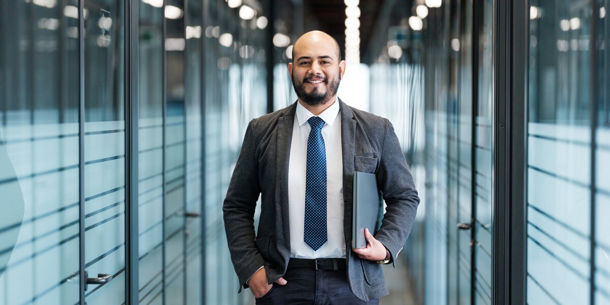 professional man smiling, in the office, holding a laptop