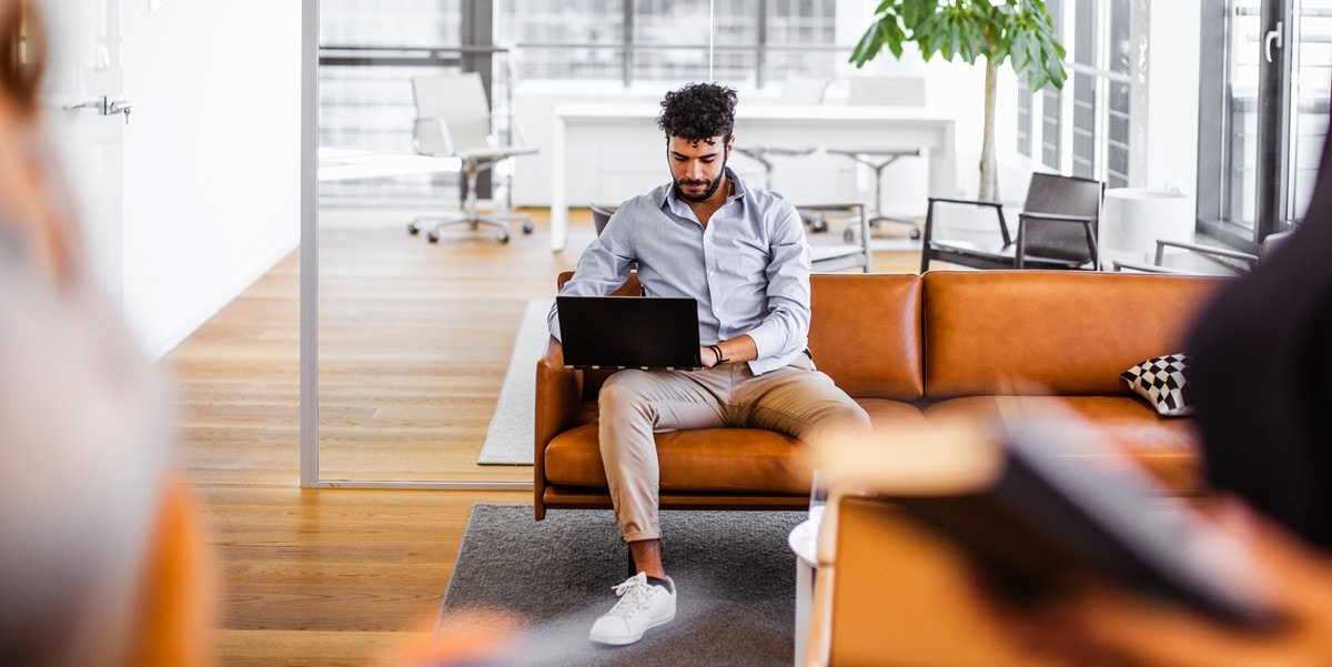 man sitting on a couch with laptop in office space