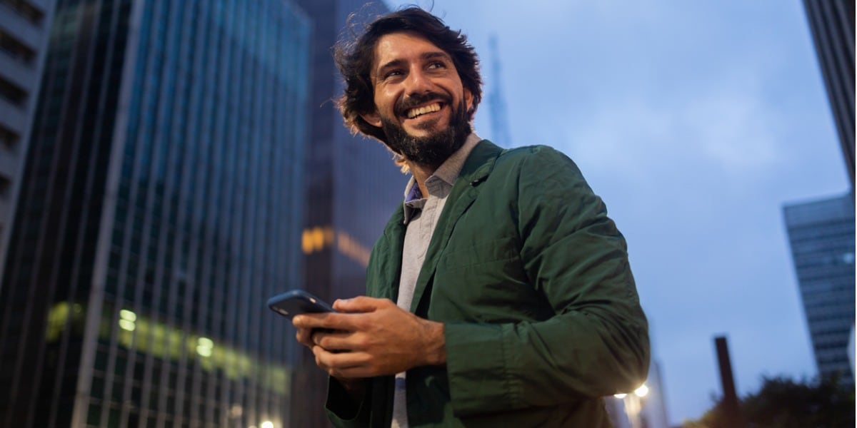 view of young man using a smartphone at night time with city view in picture