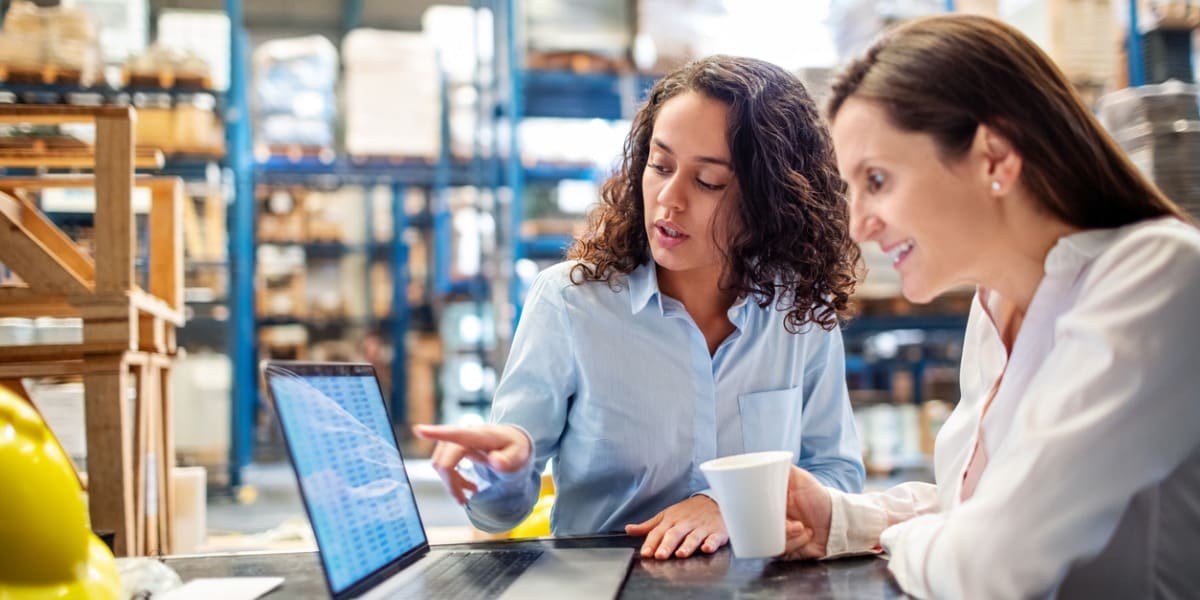 two women working and having a discussion using a laptop